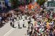 A large crowd gathers in a street in Turkey, holding colourful flags and banners during an Alevi demonstration.