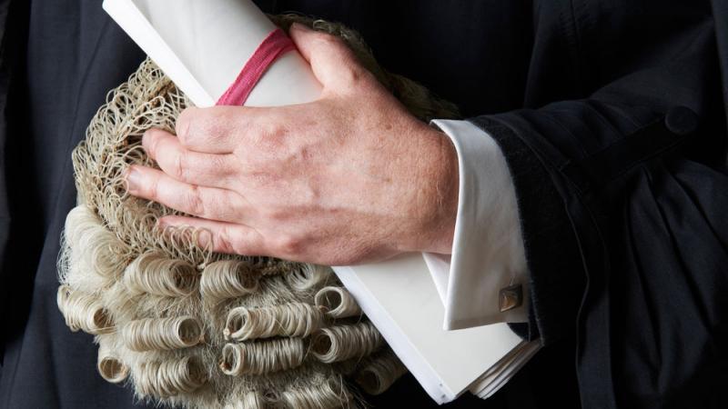Hand holding a barrister wig and rolled documents