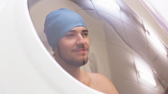 An athlete sitting in the BodPod chamber - a pod with a glass window. The athlete is smiling.