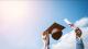 A graduate lifts their cap and scroll in the air