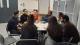 A group of PhD researchers and industry professionals sitting around a table in discussion.