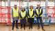 From left to right: Professor Peter Bonfield, Professor Lynne Berry CBE, Linsey Cole and Richard Dobson at Zone29. They are wearing white hard hats and yellow high-vis jackets.