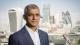 Headshot of Mayor of London Sadiq Khan with London skyline in background