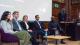 A photo of the panellists sat on chairs in front of a projector screen. To the right, Dr Mykaell Riley stands at a podium moderating the panel.