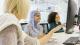 Three female students sat in desk chairs looking at computer screen