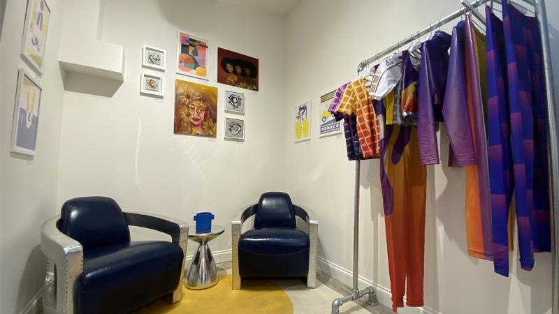 Manon Planche and Emily Eby's pop-up shop with a rack of colourful clothes, 2 chairs and some artwork