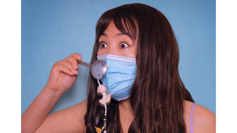 Person wearing surgical mask trying to eat cereal