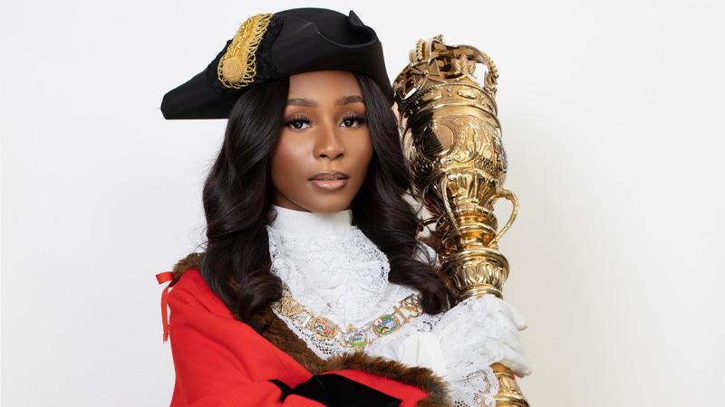 Councillor Princess Bright holding a golden sceptre in the traditional Mayor's outfit..