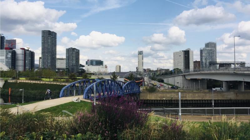 Bridge over a river with buildings and grass surrounding it