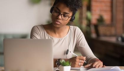 Student taking notes while attending an online event